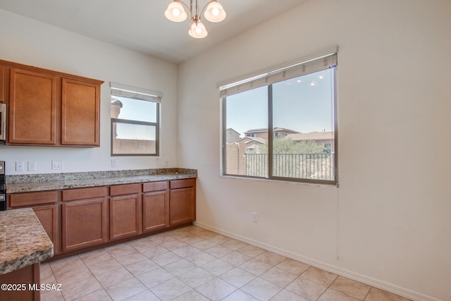 13391 N Flaxleaf Pl, Oro Valley, AZ 85755 - kitchen featuring brown cabinets, a chandelier, light stone countertops, baseboards, and light tile patterned flooring