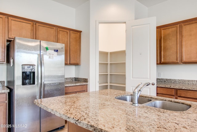 13391 N Flaxleaf Pl, Oro Valley, AZ 85755 - kitchen with stainless steel refrigerator with ice dispenser, a sink, brown cabinetry, and light stone countertops