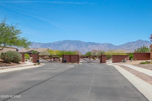 13391 N Flaxleaf Pl, Oro Valley, AZ 85755 - view of asphalt road featuring a gate, a gated entry, sidewalks, a mountain view, and curbs
