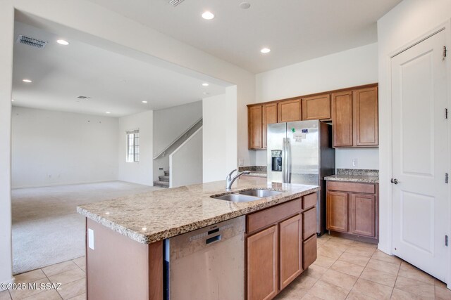 13391 N Flaxleaf Pl, Oro Valley, AZ 85755 - kitchen with appliances with stainless steel finishes, a sink, light tile patterned flooring, a center island with sink, and brown cabinets
