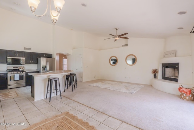 6805 W Tombstone Way, Tucson, AZ 85743 - kitchen featuring stainless steel appliances, light carpet, arched walkways, high vaulted ceiling, and a kitchen bar
