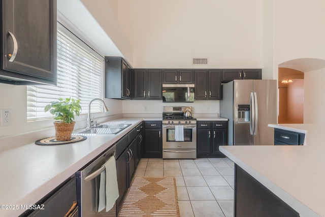 6805 W Tombstone Way, Tucson, AZ 85743 - kitchen featuring stainless steel appliances, a sink, light countertops, arched walkways, and light tile patterned flooring