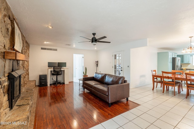 2501 W Calle Paraiso, Tucson, AZ 85745 - living room featuring ceiling fan, light wood-style floors, a stone fireplace, recessed lighting, and a chandelier