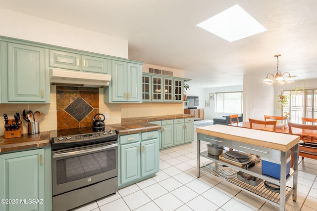 2501 W Calle Paraiso, Tucson, AZ 85745 - kitchen with stainless steel range with electric cooktop, under cabinet range hood, a skylight, backsplash, and a chandelier