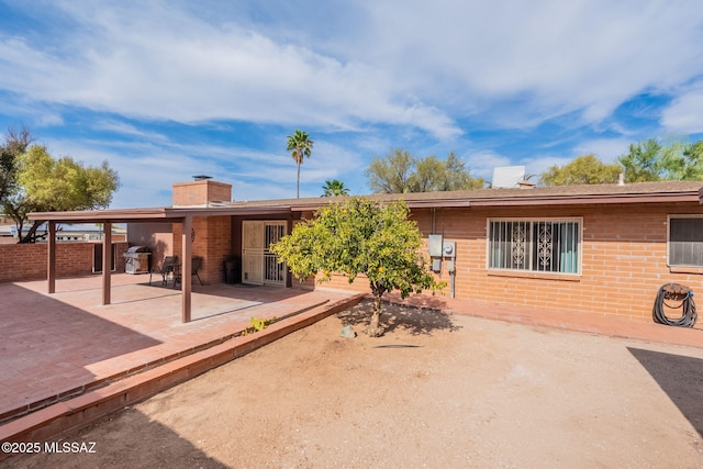 2501 W Calle Paraiso, Tucson, AZ 85745 - back of house featuring a patio, a chimney, and brick siding