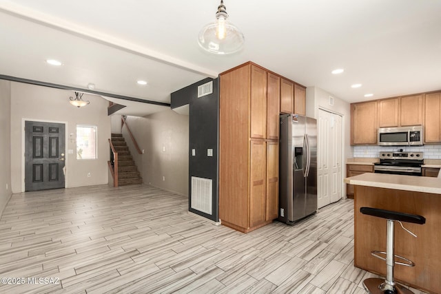 318 N Hasman Dr, Tucson, AZ 85745 - kitchen with stainless steel appliances, light countertops, light wood-style flooring, tasteful backsplash, and pendant lighting