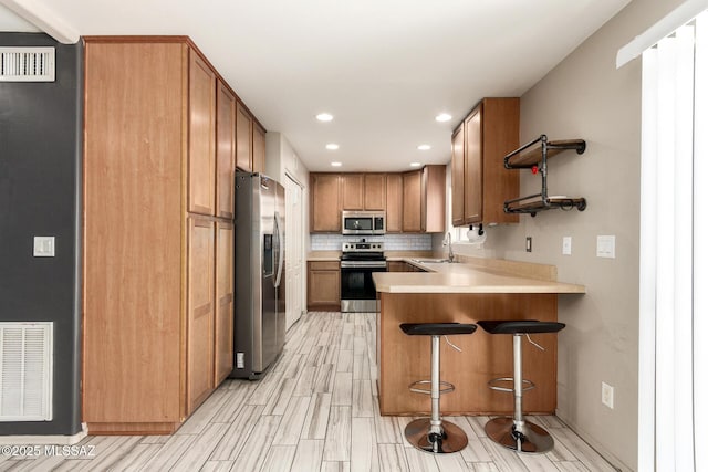 318 N Hasman Dr, Tucson, AZ 85745 - kitchen featuring appliances with stainless steel finishes, a peninsula, light countertops, a kitchen breakfast bar, and recessed lighting