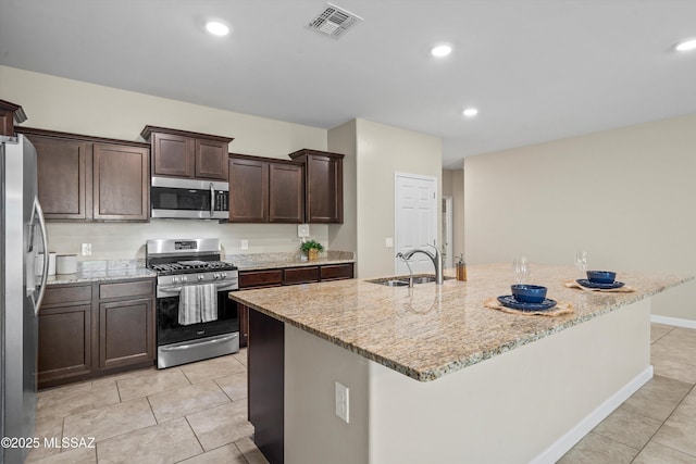 12223 E Becker Dr, Vail, AZ 85641 - kitchen with stainless steel appliances, a sink, light tile patterned flooring, dark brown cabinetry, and light stone countertops