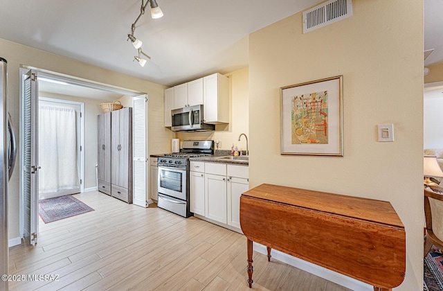 303 S Paseo Cerro Unit A, Green Valley, AZ 85614 - kitchen with stainless steel appliances, white cabinetry, light wood-style floors, and a sink