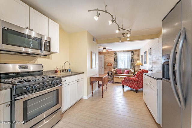 303 S Paseo Cerro Unit A, Green Valley, AZ 85614 - kitchen featuring appliances with stainless steel finishes, dark countertops, brick wall, and white cabinets