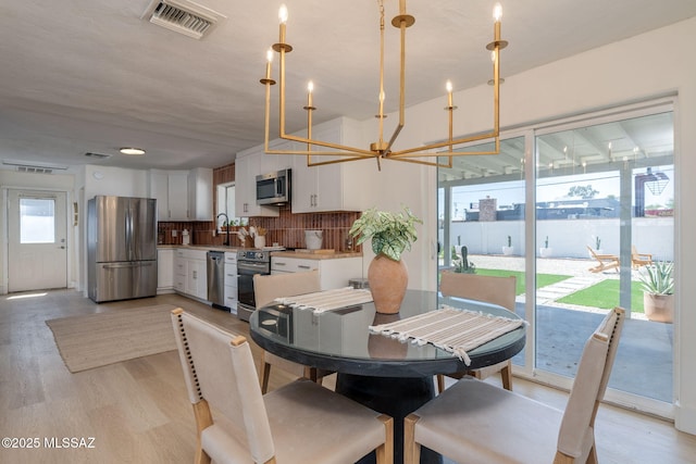 5762 E Helen St, Tucson, AZ 85712 - dining room featuring light wood-style floors and a chandelier