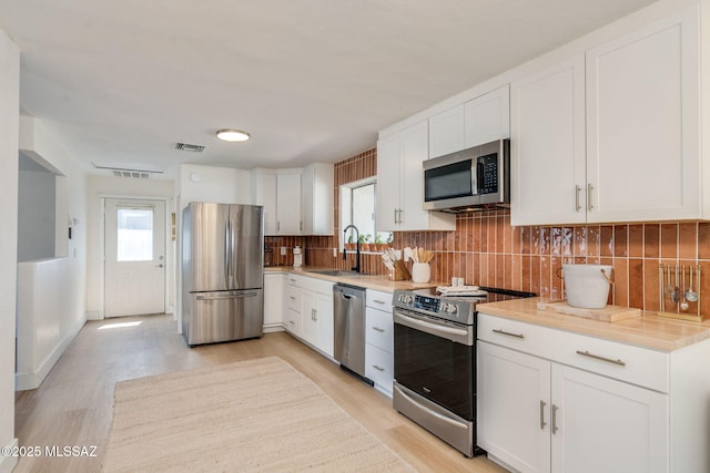 5762 E Helen St, Tucson, AZ 85712 - kitchen with appliances with stainless steel finishes, light wood-style floors, tasteful backsplash, light countertops, and white cabinetry