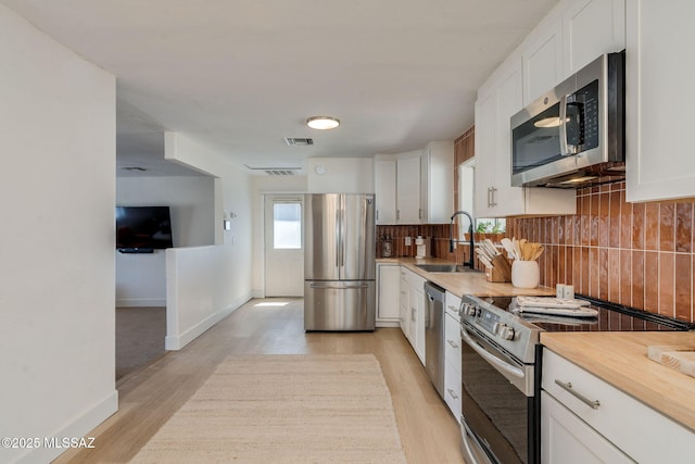 5762 E Helen St, Tucson, AZ 85712 - kitchen featuring appliances with stainless steel finishes, a sink, backsplash, and light wood-type flooring