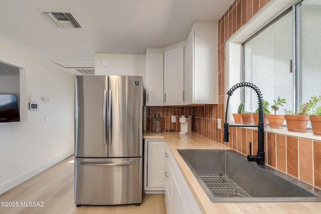 5762 E Helen St, Tucson, AZ 85712 - kitchen featuring freestanding refrigerator, a sink, white cabinets, tasteful backsplash, and light countertops
