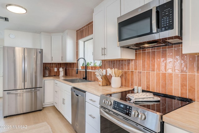 5762 E Helen St, Tucson, AZ 85712 - kitchen featuring stainless steel appliances, a sink, light countertops, white cabinets, and decorative backsplash