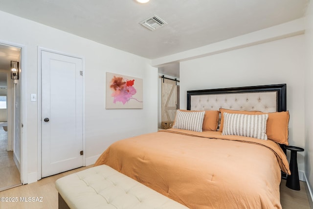 5762 E Helen St, Tucson, AZ 85712 - bedroom featuring a barn door, wood finished floors, and baseboards