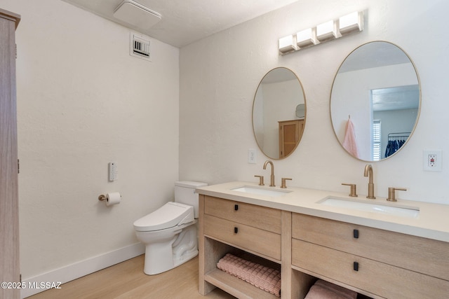 5762 E Helen St, Tucson, AZ 85712 - full bathroom with wood finished floors, double vanity, toilet, and baseboards