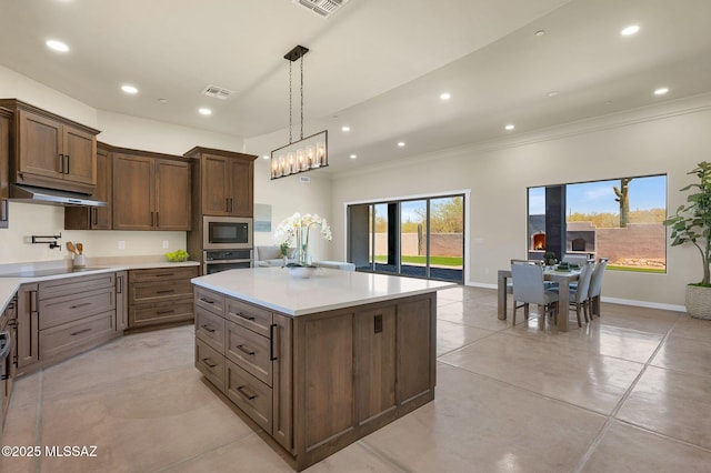 976 W Las Lomitas Rd, Tucson, AZ 85704 - kitchen featuring built in microwave, crown molding, light countertops, light tile patterned floors, and a center island
