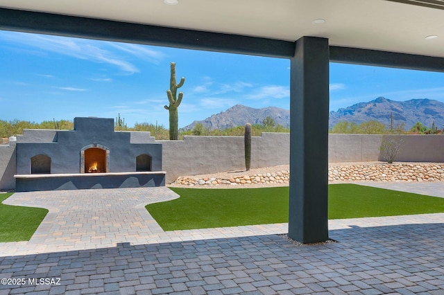 976 W Las Lomitas Rd, Tucson, AZ 85704 - fenced backyard featuring a warm lit fireplace, a mountain view, and a patio