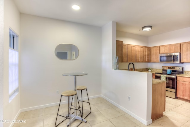 1500 E Pusch Wilderness Dr Unit 10106, Tucson, AZ 85737 - kitchen featuring stainless steel appliances, light tile patterned floors, a sink, and brown cabinetry