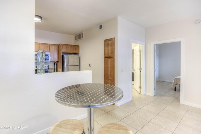 1500 E Pusch Wilderness Dr Unit 10106, Tucson, AZ 85737 - kitchen featuring freestanding refrigerator, brown cabinets, light tile patterned floors, range, and baseboards
