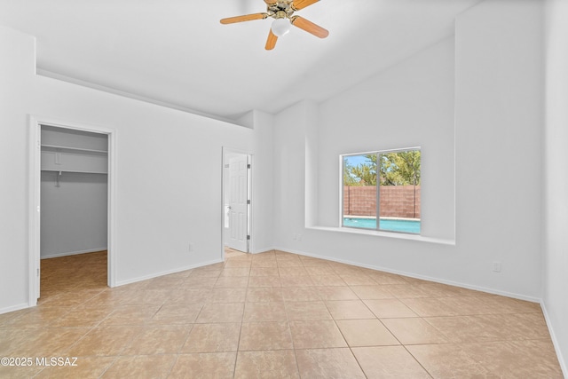 1562 W Via De Chapala, Sahuarita, AZ 85629 - unfurnished bedroom with high vaulted ceiling, light tile patterned floors, a spacious closet, baseboards, and ceiling fan