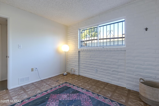 4557 E San Francisco Blvd, Tucson, AZ 85712 - unfurnished room featuring a textured ceiling and brick wall
