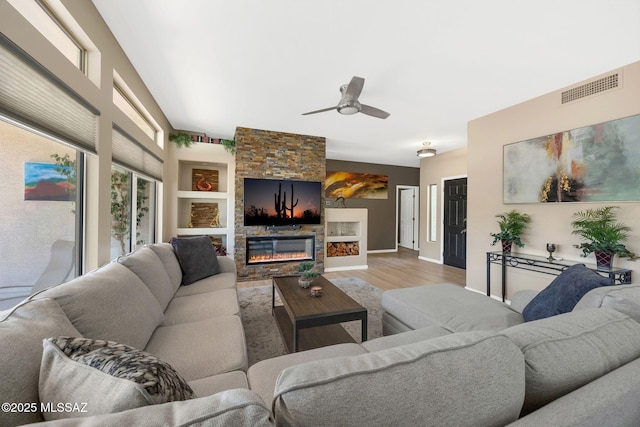 37671 S Hill Side Dr, Tucson, AZ 85739 - living room with wood finished floors, ceiling fan, a stone fireplace, baseboards, and built in features