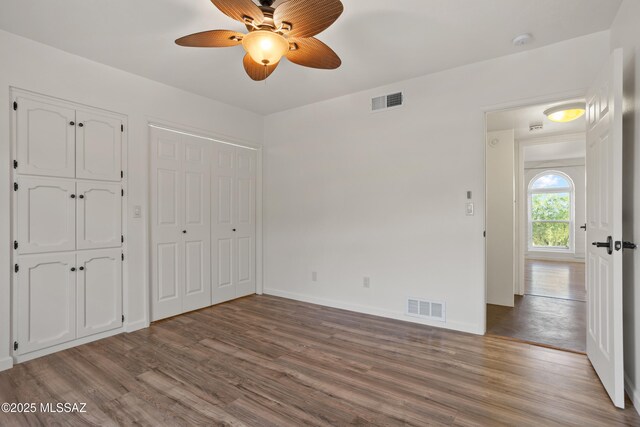 6355 N Camino De Santa Valera, Tucson, AZ 85718 - unfurnished bedroom featuring wood finished floors, multiple closets, baseboards, and ceiling fan