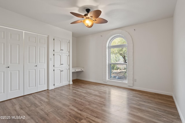 6355 N Camino De Santa Valera, Tucson, AZ 85718 - unfurnished bedroom featuring two closets, wood finished floors, baseboards, and a ceiling fan