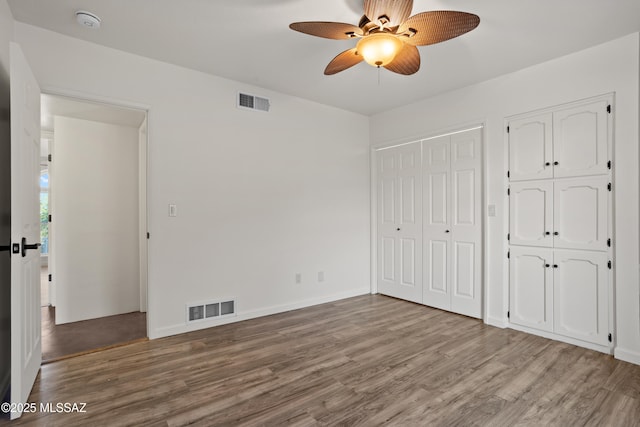 6355 N Camino De Santa Valera, Tucson, AZ 85718 - unfurnished bedroom with wood finished floors, two closets, baseboards, and ceiling fan