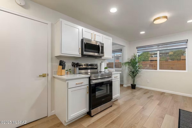 5601 E Baker St, Tucson, AZ 85711 - kitchen featuring stainless steel appliances, light wood-type flooring, light countertops, white cabinetry, and baseboards
