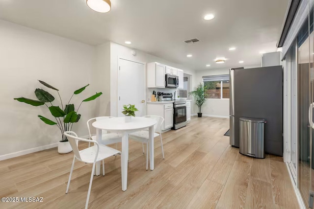 5601 E Baker St, Tucson, AZ 85711 - kitchen with stainless steel appliances, white cabinets, baseboards, light wood finished floors, and recessed lighting