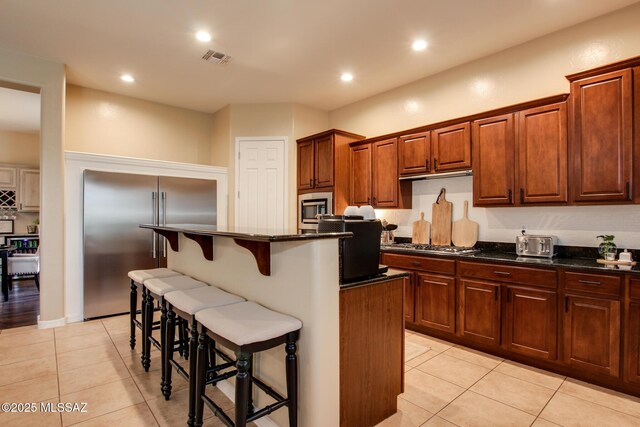 5457 S Canyon Oak Dr, Tucson, AZ 85747 - kitchen featuring built in appliances, light tile patterned floors, a breakfast bar area, dark stone counters, and recessed lighting