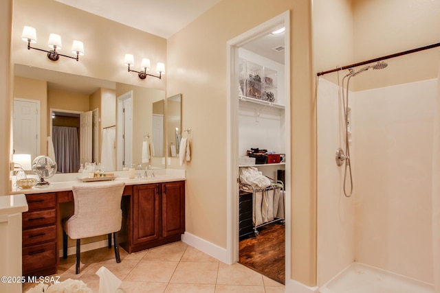 5457 S Canyon Oak Dr, Tucson, AZ 85747 - bathroom with tile patterned flooring, vanity, walk in shower, a spacious closet, and baseboards