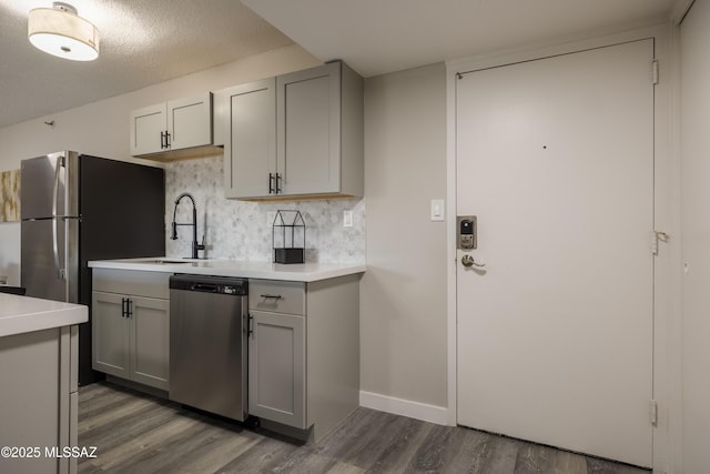 425 W Paseo Redondo Unit 3D, Tucson, AZ 85701 - kitchen featuring stainless steel dishwasher, gray cabinetry, wood finished floors, backsplash, and light countertops