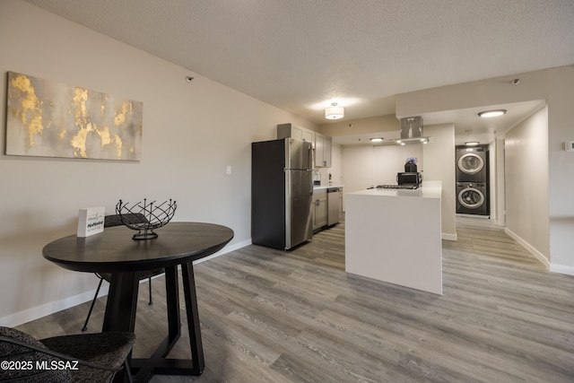 425 W Paseo Redondo Unit 3D, Tucson, AZ 85701 - kitchen featuring appliances with stainless steel finishes, stacked washing machine and dryer, wood finished floors, a textured ceiling, and light countertops