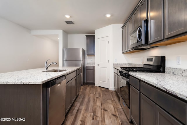 21917 E Wayward Ln, Red Rock, AZ 85145 - kitchen featuring stainless steel appliances, dark wood-style flooring, a center island with sink, light stone countertops, and recessed lighting