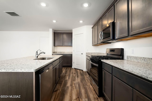 21903 E Wayward Ln, Red Rock, AZ 85145 - kitchen featuring stainless steel appliances, dark wood finished floors, light stone counters, dark brown cabinets, and a kitchen island with sink