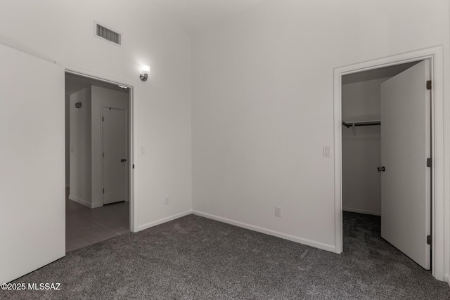 8072 S Carbury Way, Tucson, AZ 85747 - unfurnished bedroom with dark carpet, a walk in closet, and baseboards