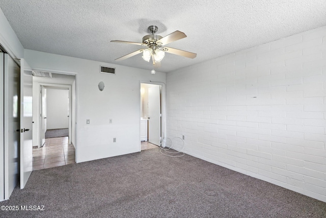 1358 S Desert Meadows Cir, Green Valley, AZ 85614 - unfurnished bedroom with carpet flooring, a textured ceiling, ensuite bathroom, brick wall, and a ceiling fan
