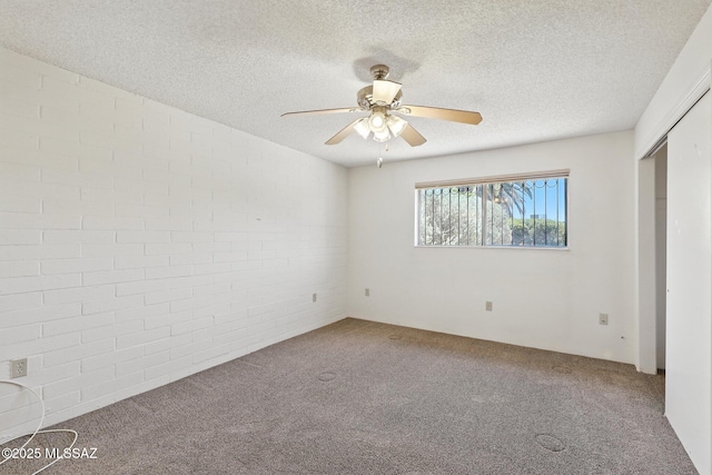 1358 S Desert Meadows Cir, Green Valley, AZ 85614 - unfurnished bedroom featuring carpet floors, brick wall, a textured ceiling, a ceiling fan, and a closet