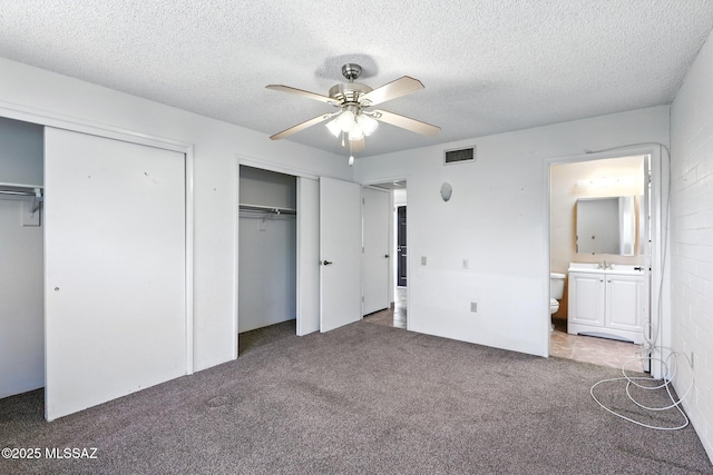 1358 S Desert Meadows Cir, Green Valley, AZ 85614 - unfurnished bedroom with two closets, carpet floors, a textured ceiling, connected bathroom, and a ceiling fan