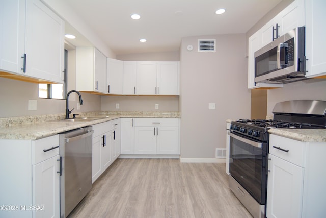 1321 W Saint Clair St, Tucson, AZ 85745 - kitchen with appliances with stainless steel finishes, a sink, light wood finished floors, recessed lighting, and white cabinets