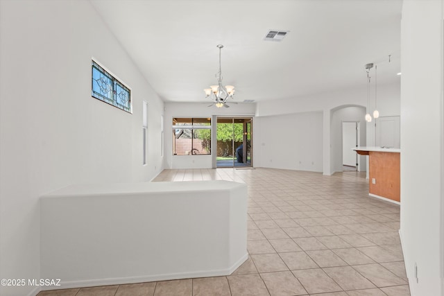 215 E Placita Lago Del Mago, Sahuarita, AZ 85629 - unfurnished living room featuring a chandelier, arched walkways, and light tile patterned flooring