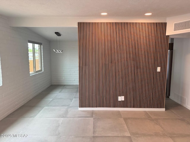 516 E Linden St, Tucson, AZ 85705 - empty room featuring brick wall and a textured ceiling