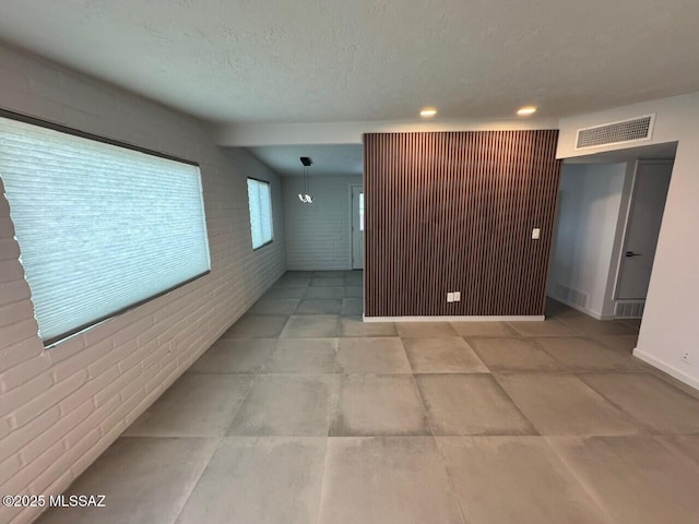516 E Linden St, Tucson, AZ 85705 - unfurnished room with brick wall, a textured ceiling, and recessed lighting