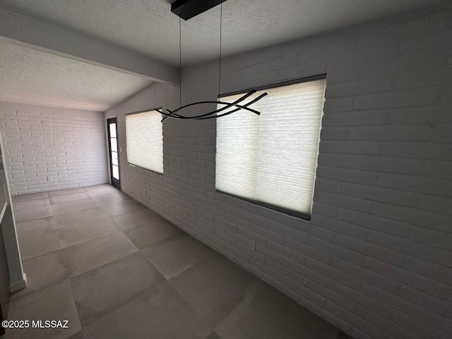 516 E Linden St, Tucson, AZ 85705 - unfurnished dining area featuring a textured ceiling, brick wall, and beam ceiling
