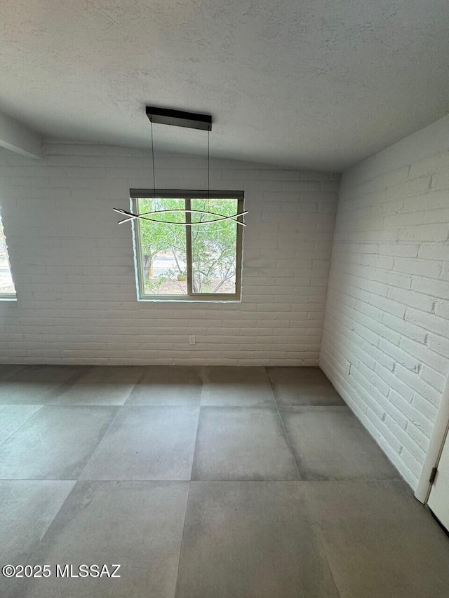 516 E Linden St, Tucson, AZ 85705 - unfurnished room with brick wall, plenty of natural light, and a textured ceiling