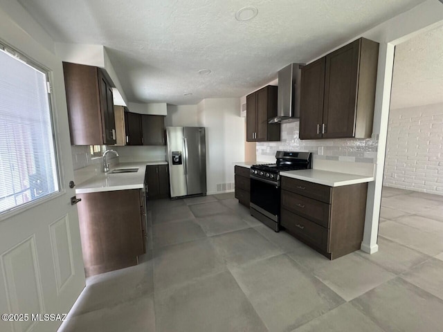 516 E Linden St, Tucson, AZ 85705 - kitchen with gas range, stainless steel refrigerator with ice dispenser, wall chimney exhaust hood, a sink, and dark brown cabinets